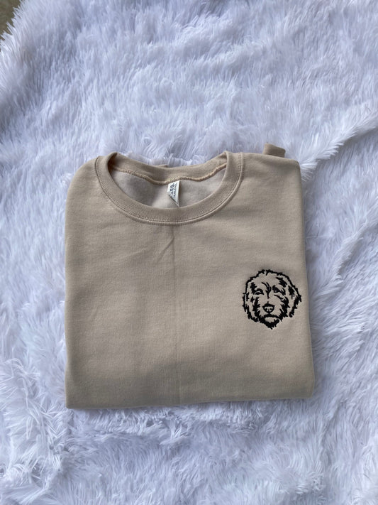 Golden Doodle Head embroidered sweatshirt on soft fabric background.