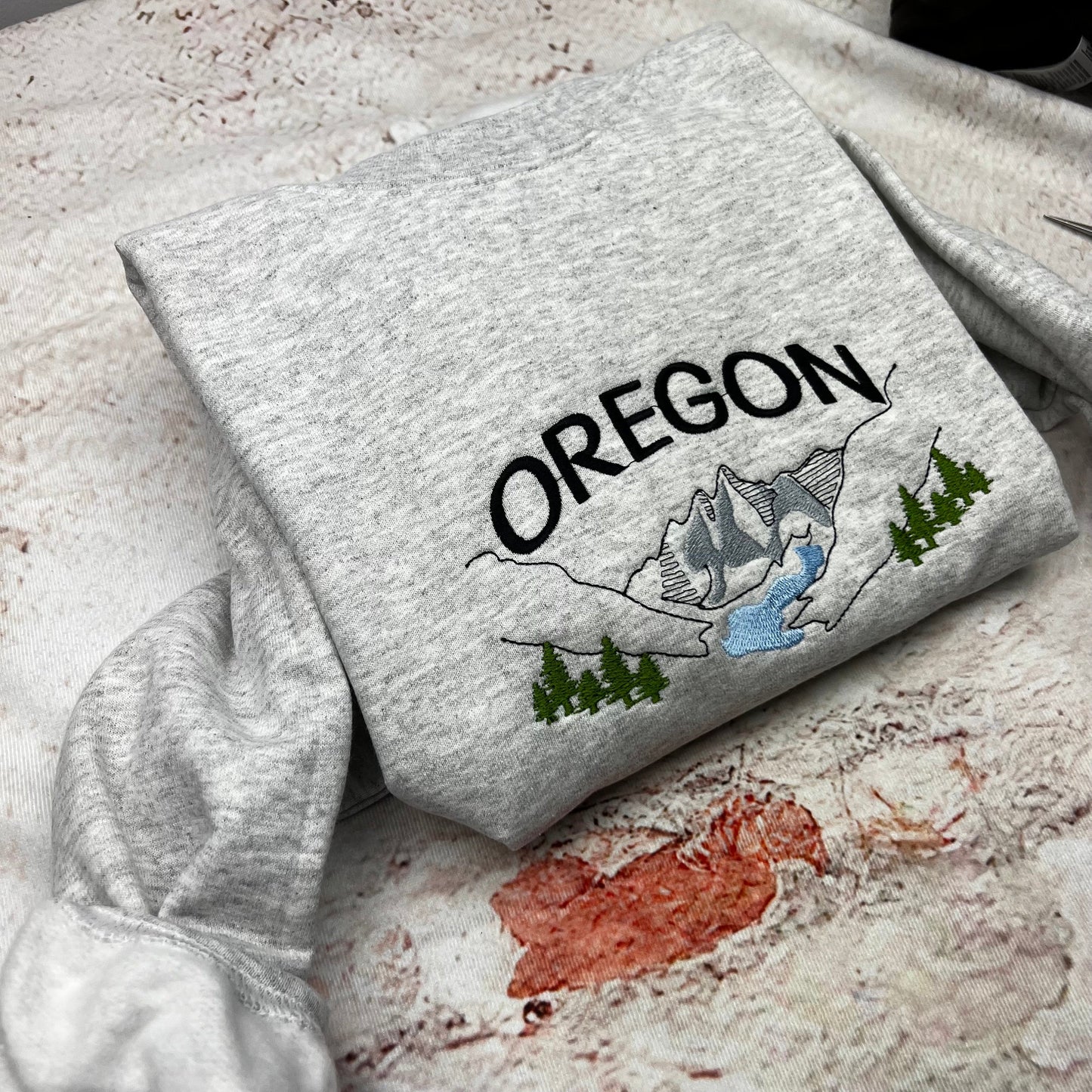 Oregon embroidered sweatshirt featuring mountain and river design.