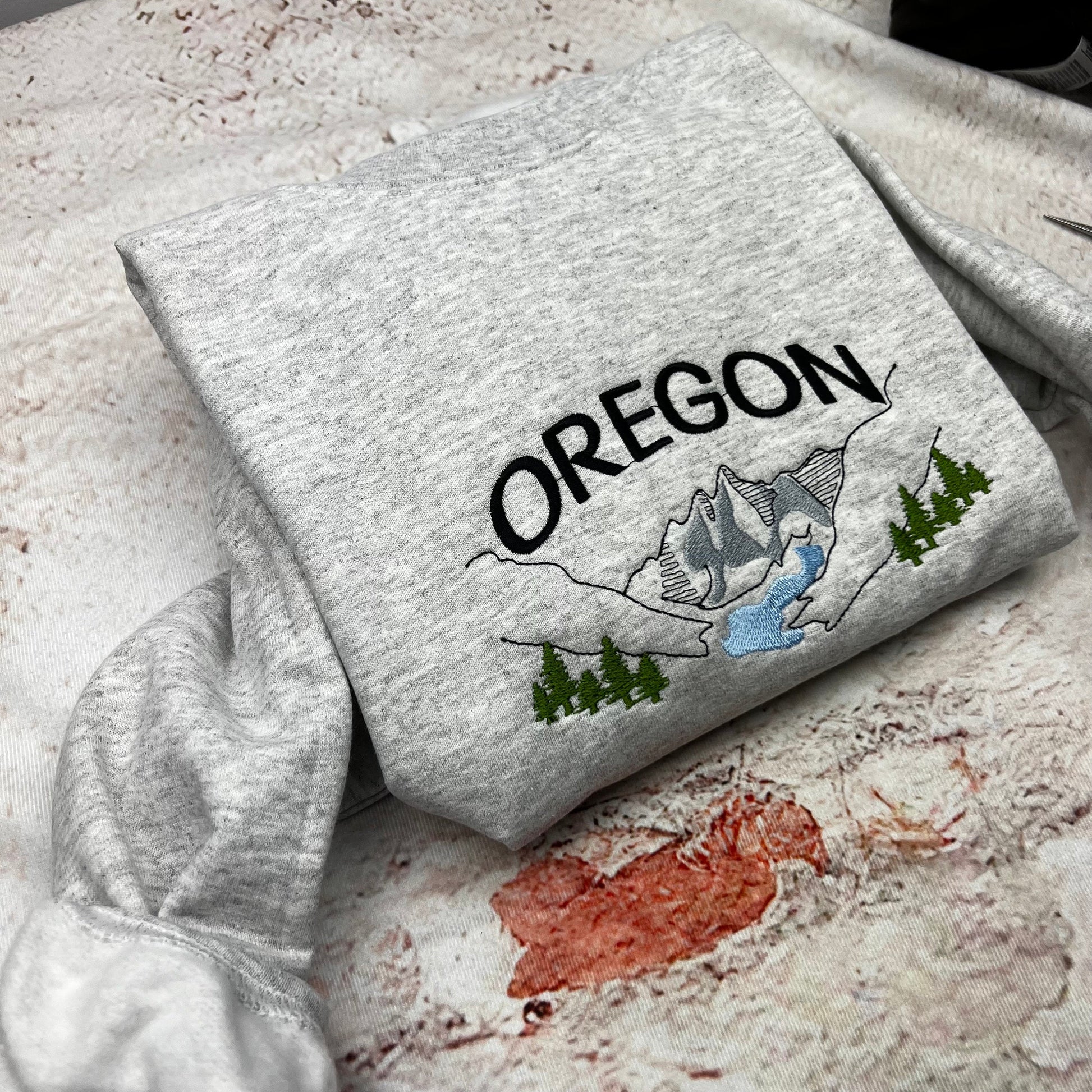Oregon embroidered sweatshirt featuring mountain and river design.