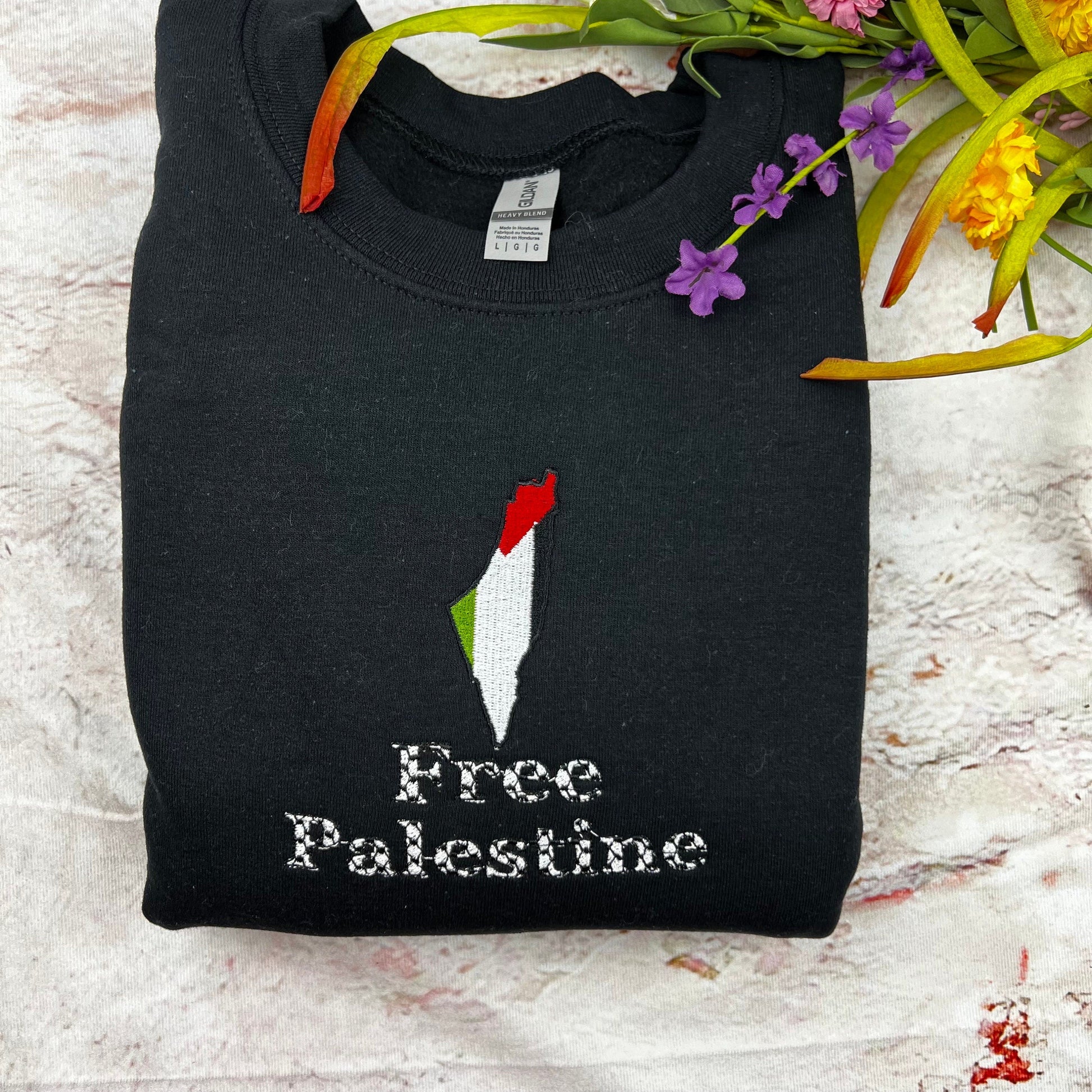 Embroidered Free Palestine crewneck sweatshirt on display with floral accents.