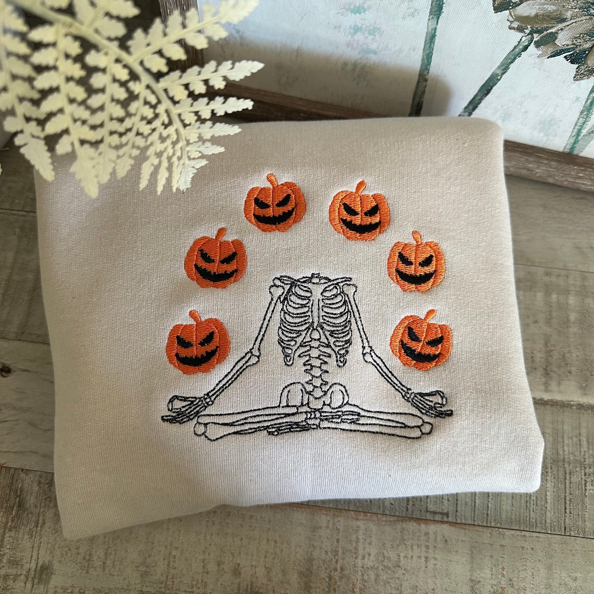 Halloween embroidered sweatshirt featuring a skeleton juggling jack-o'-lanterns.