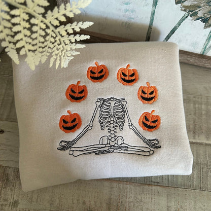 Halloween embroidered sweatshirt featuring a skeleton juggling jack-o'-lanterns.