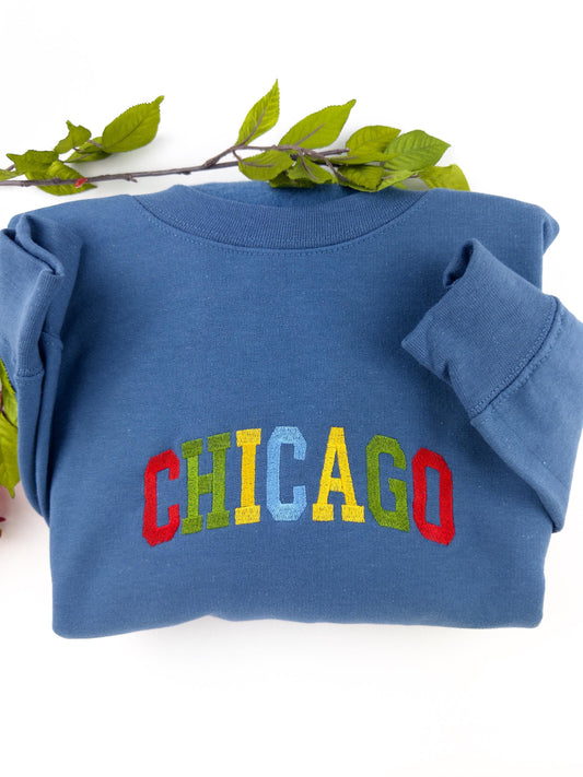Colorful "Chicago" embroidered sweatshirt in blue with vibrant multicolored lettering.