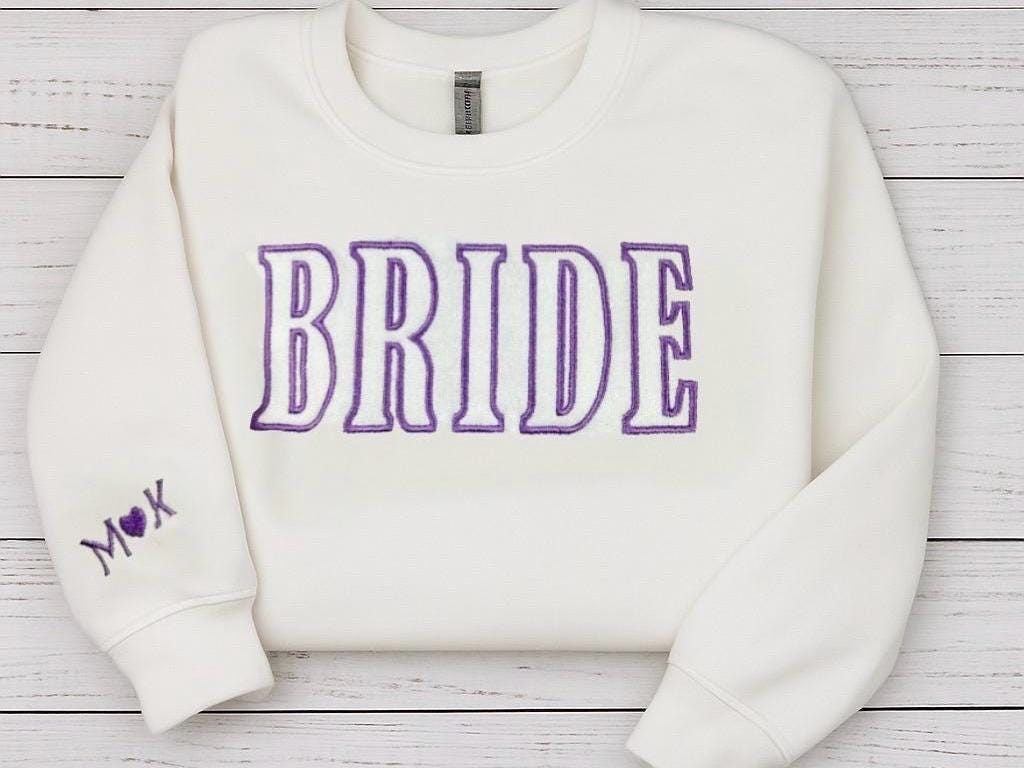 White bride sweatshirt with purple embroidery, customizable for bridal showers or wedding gifts.