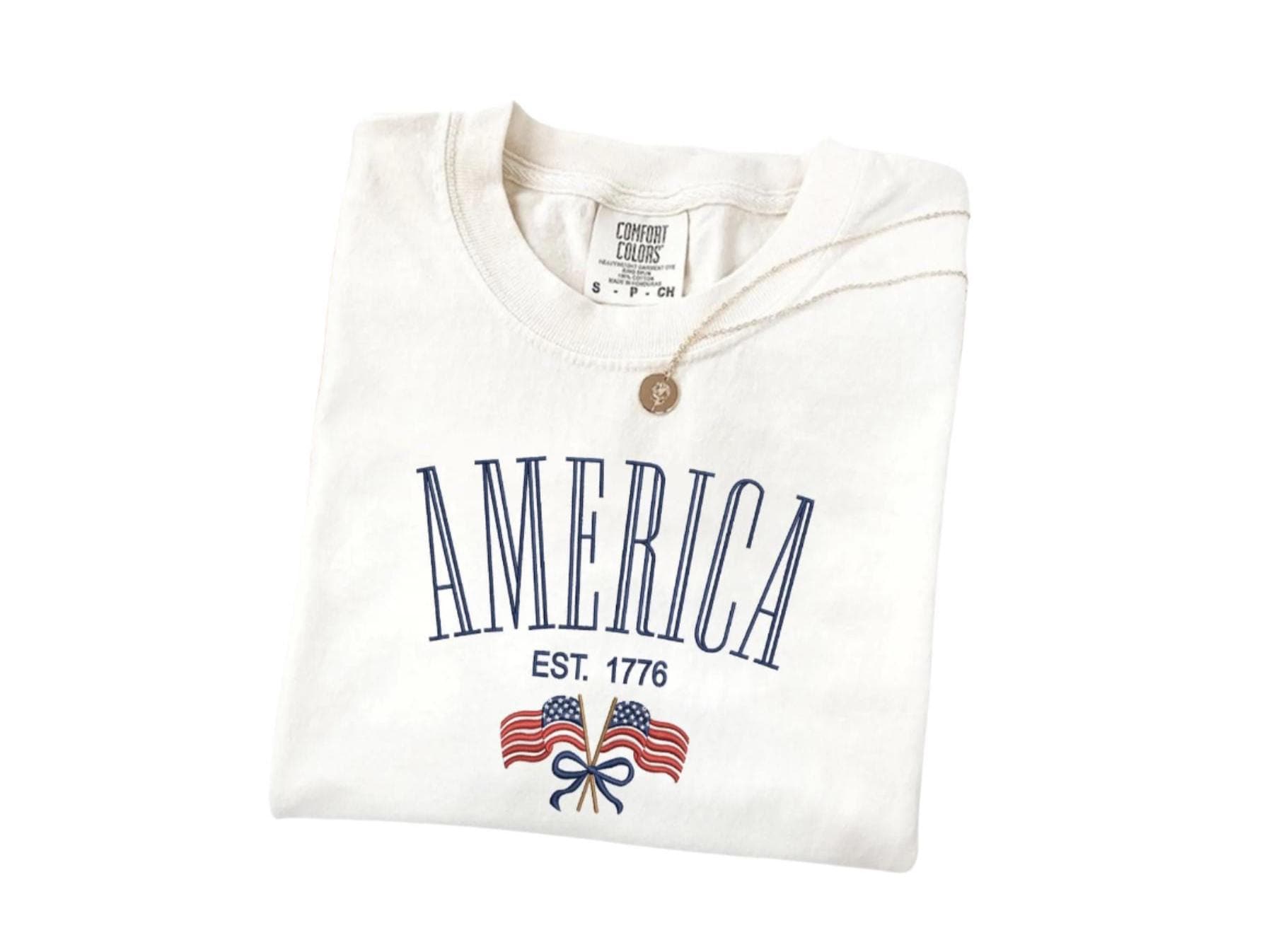 America Est. 1776 T-Shirt in ivory color, featuring vintage design with double flags, soft Comfort Colors cotton, perfect for patriotic celebrations.
