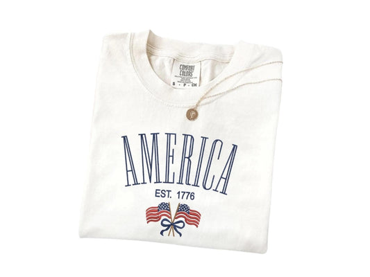 America Est. 1776 T-Shirt in ivory color, featuring vintage design with double flags, soft Comfort Colors cotton, perfect for patriotic celebrations.