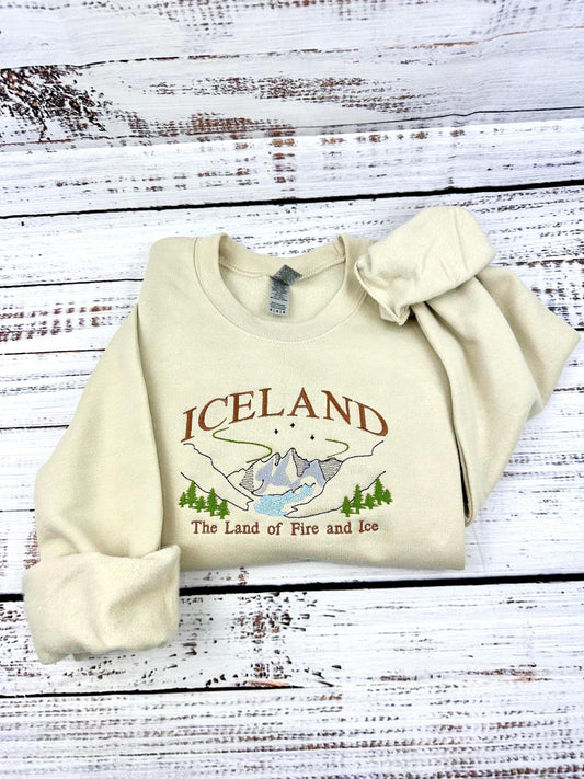 Iceland embroidered sweatshirt with Nordic mountains and aurora design, labeled "Land of Fire and Ice."