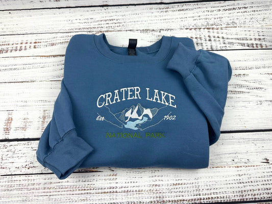 Crater Lake National Park embroidered sweatshirt on wood background.